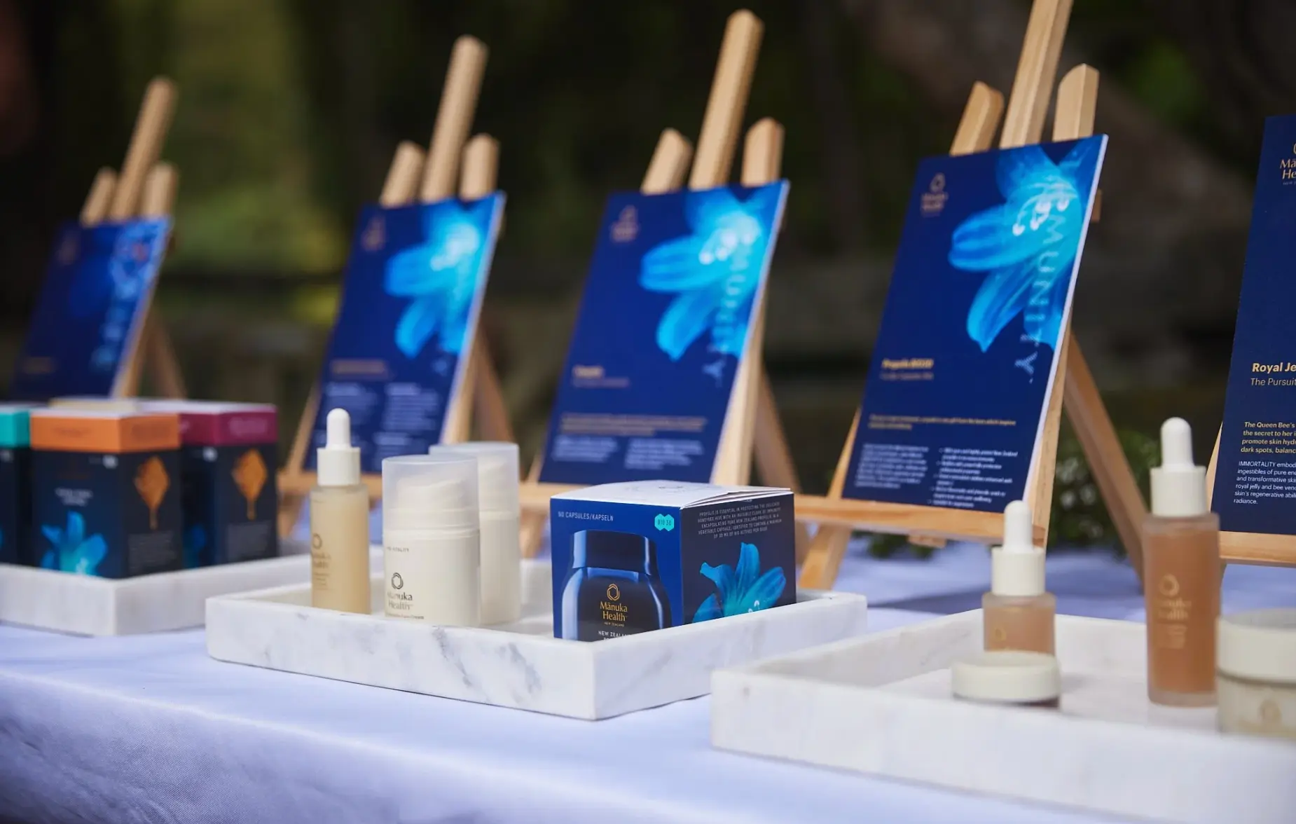 New Mānuka Health products presented on marble trays with wooden easels at a garden table