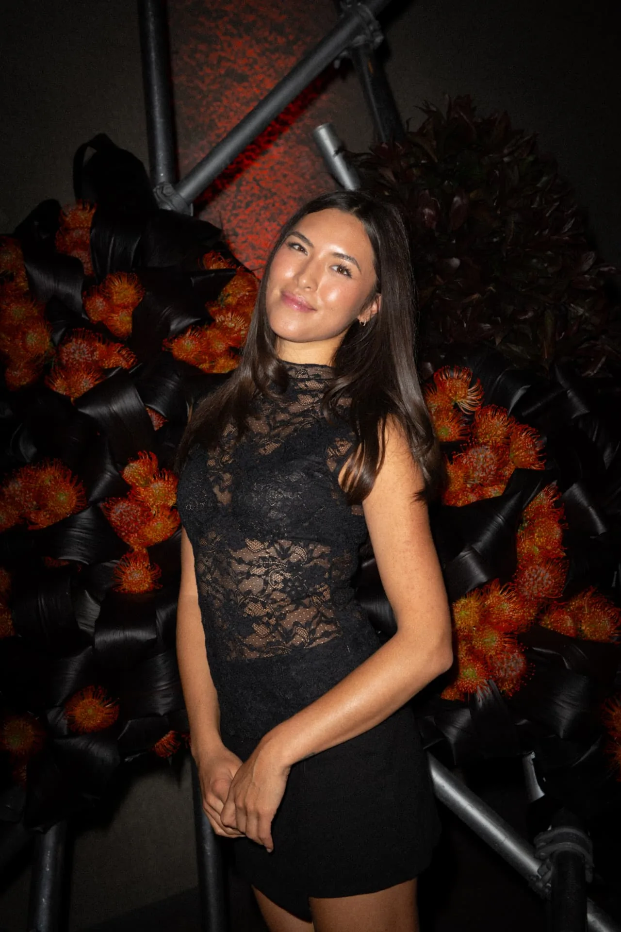 Guest in a black lace look before the sculptural floral installation at the EX NIHILO launch