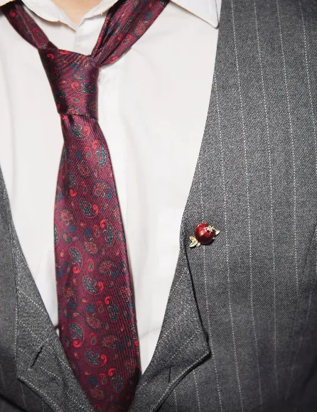 Guest in grey pinstripe tailoring wearing a pomegranate lapel pin