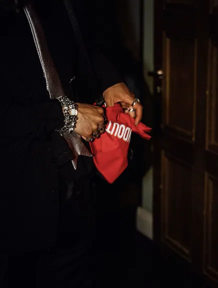 Guest holding a red BORNTOSTANDOUT game pouch