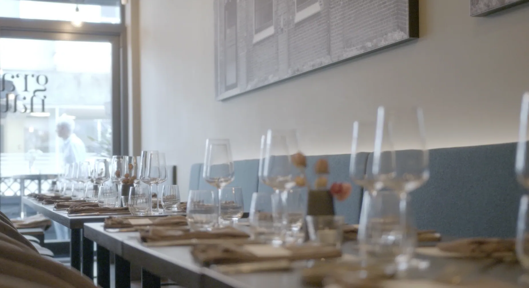 Long dinner table with glasses, linen napkins and wildflowers in a bright nordic restaurant