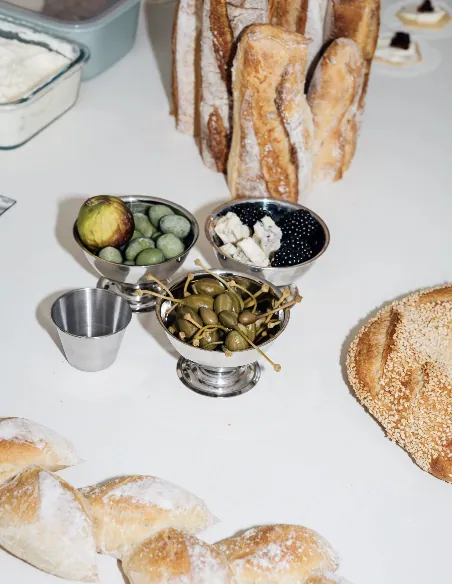 Minimalist food installation with breads, olives, figs and blackberries