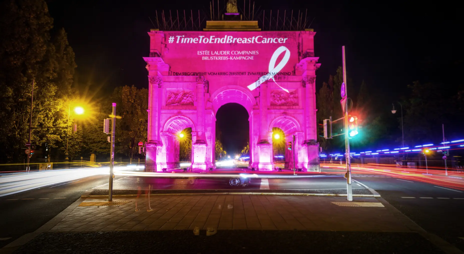 Pink illumination of a landmark at night with passing traffic light trails