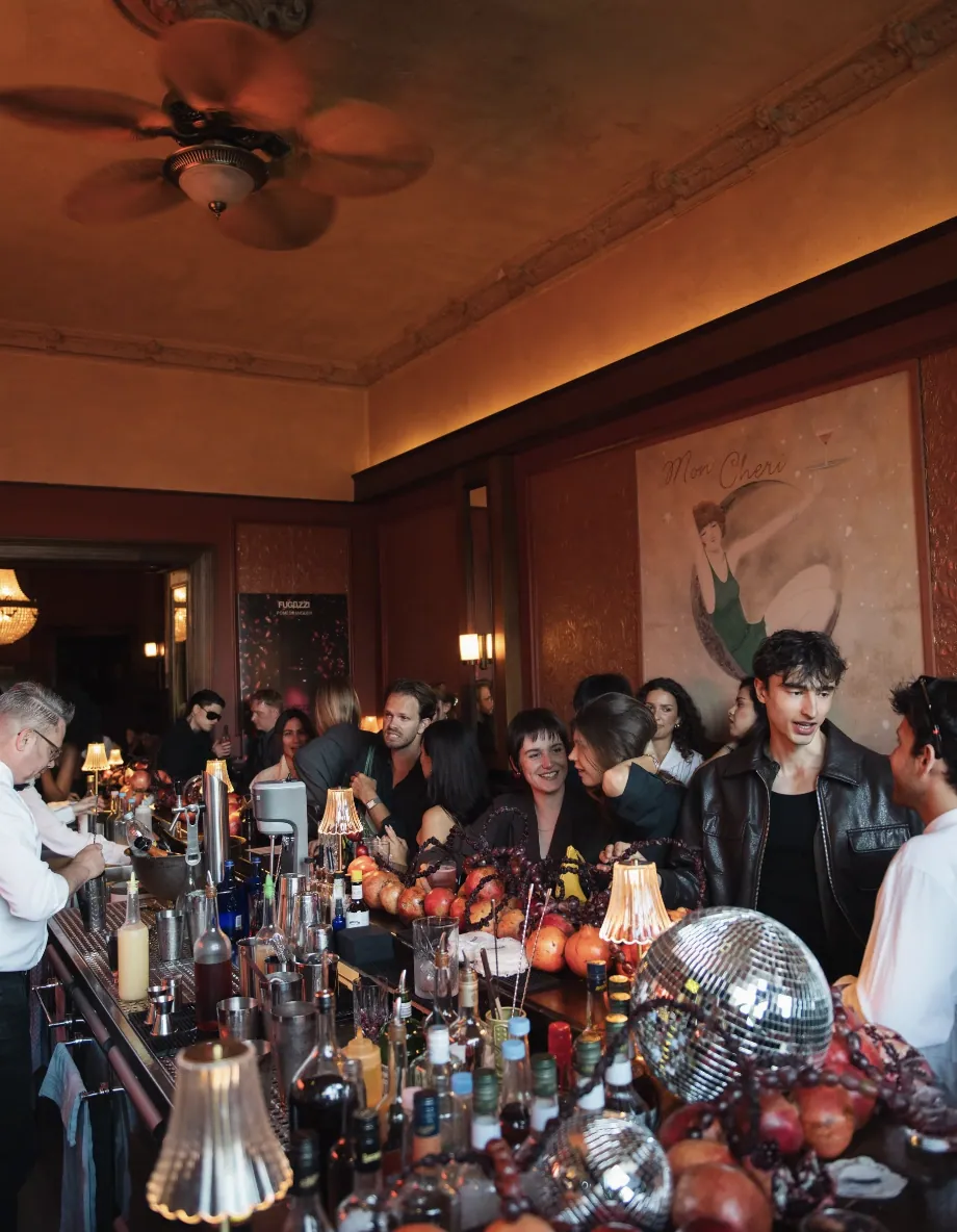 Guests gathered along the pomegranate-covered bar beneath the glowing FUGAZZI neon sign